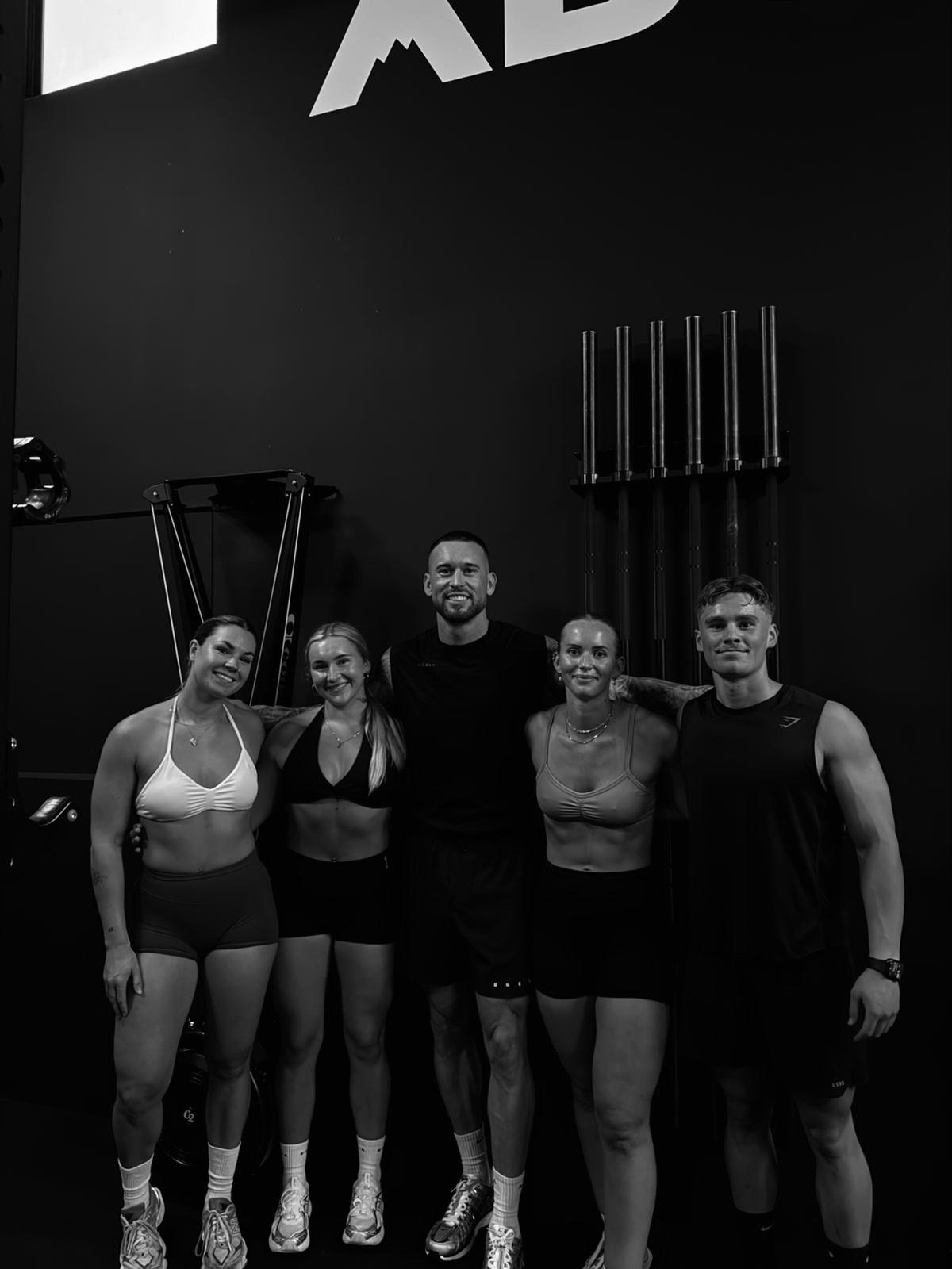 Smiling Above Gym members with coach in front of the Above wall