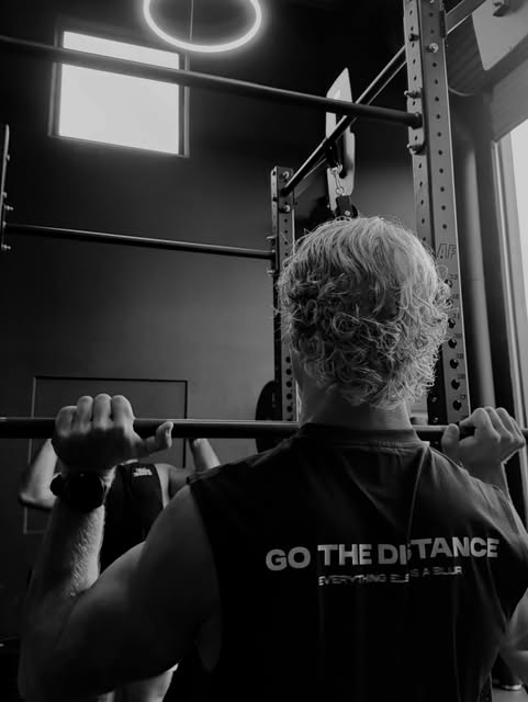 Member squatting under halo light in the rack