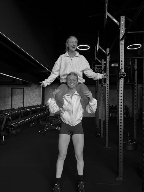 Two laughing members, one on the other's shoulders