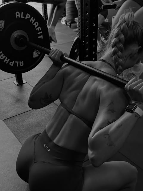Member performing a back squat with weight plate close up